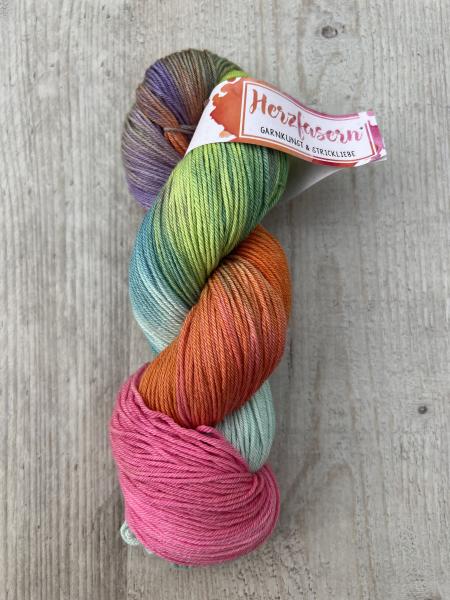 Alternativtext Bild: Strang handgefärbte Wolle in Pink, Orange, Grün und Blau, Herzfasern No. 92 Herz & Seele – Regenbogenkuss. 	•	Kontraste: Holzhintergrund bietet guten Kontrast, Farben klar erkennbar. 	•	Shop-Text: gut lesbar in mind. 16 px, klare Glie